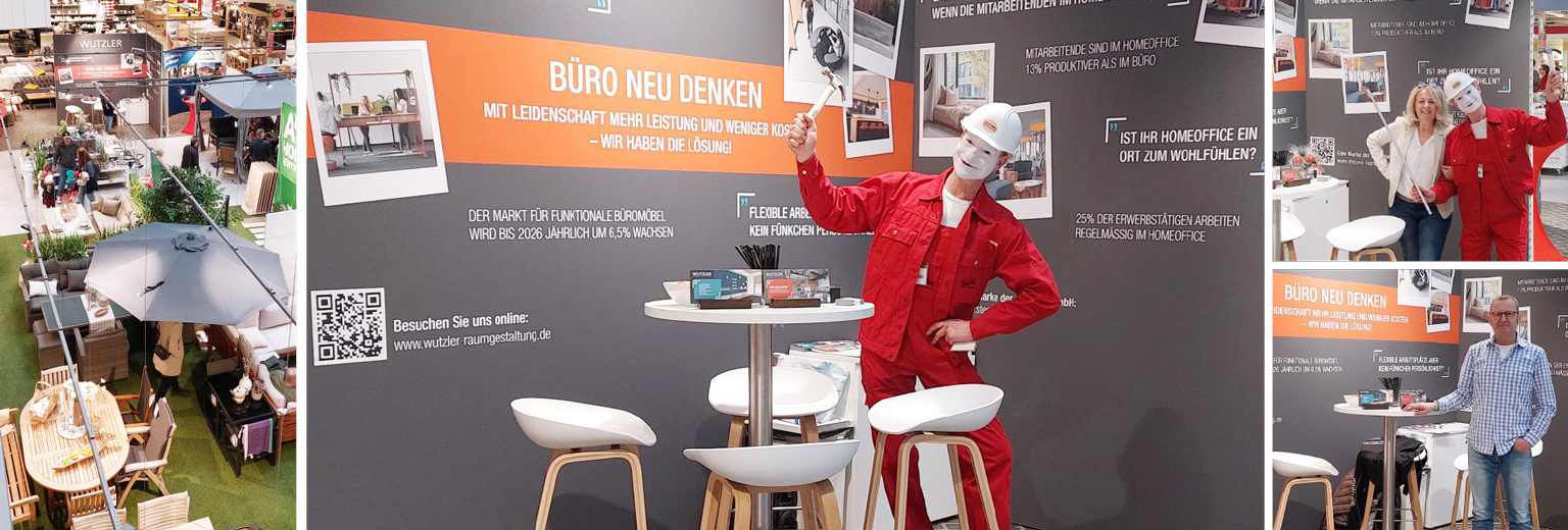 Messestand von Wutzler Raumgestaltung mit dem Motto „Büro neu denken“; ein Performer in rotem Overall und Helm sorgt mit Pantomime für Aufmerksamkeit.