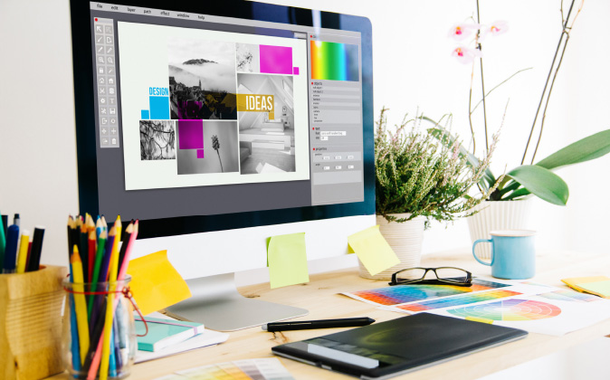 Ein aufgeräumter, kreativer Arbeitsplatz mit iMac, Grafikdesign-Software, Farbpaletten und Zeichenstift – Designprozess bei der step one GmbH.