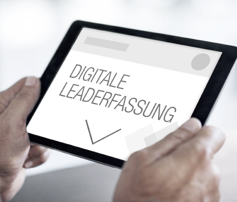 Nahaufnahme eines Tablets, das von zwei Händen gehalten wird. Auf dem Bildschirm ist der Text „DIGITALE LEADERFASSUNG“ mit einem großen Pfeil nach unten zu sehen, was auf eine digitale Erfassungslösung hinweist.