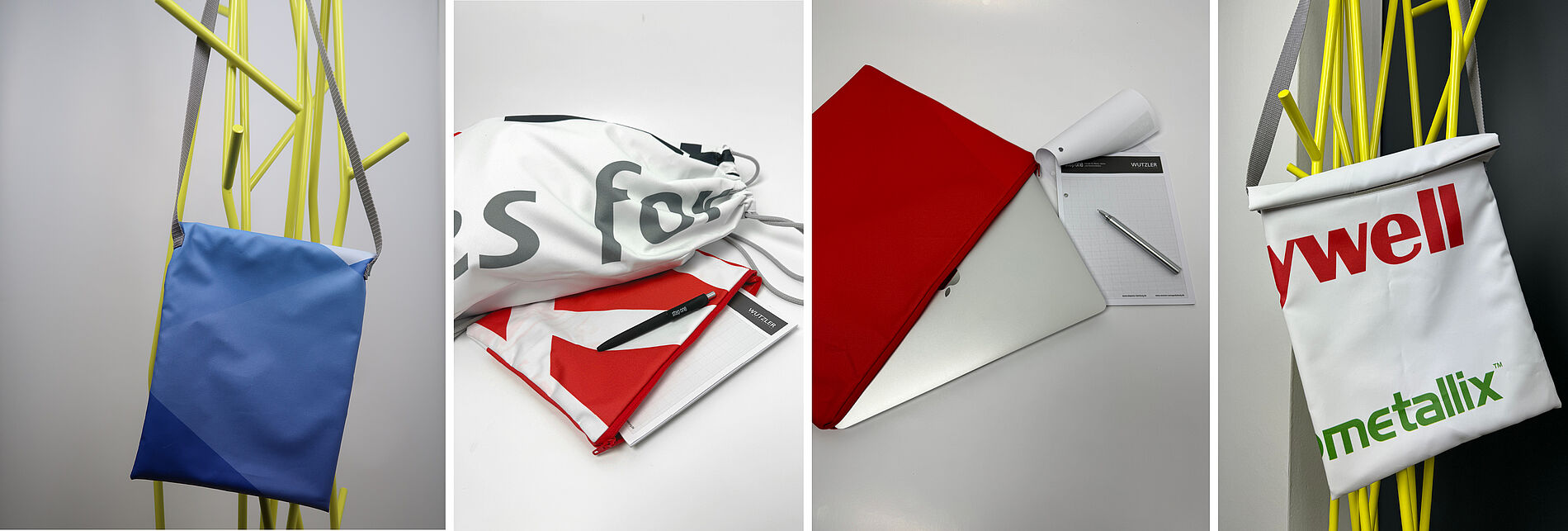 Vier verschiedene Upcycling-Taschen aus recycelten Werbebannern: eine blaue Umhängetasche an gelbem Garderobenständer, ein weiß-roter Turnbeutel mit Schreibblock und Stift, ein roter Laptop-Sleeve mit MacBook und Notizblock, eine weiße Tasche mit rotem und grünem Text an gelbem Gestell.